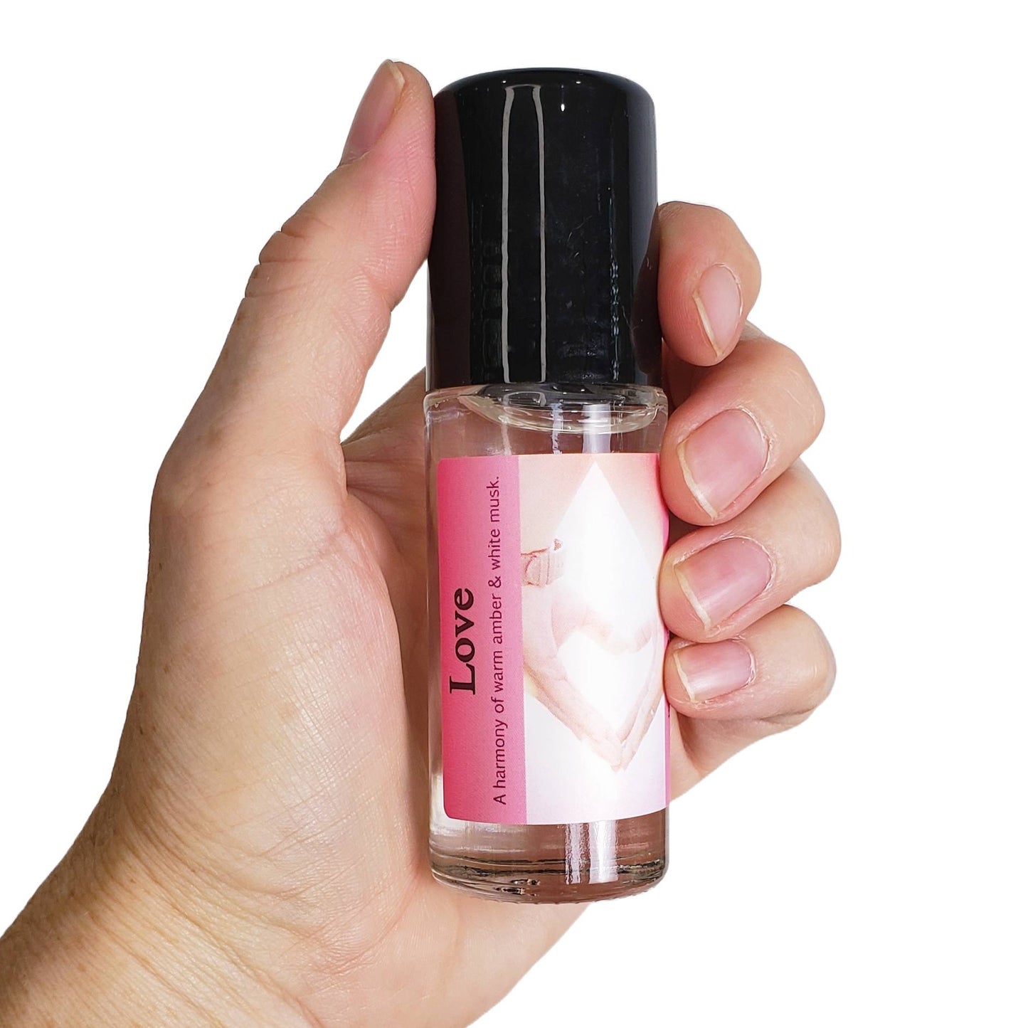 a hand holding love perfume oil, the large 1 ounce bottle, a blend of amber and musk fragrances