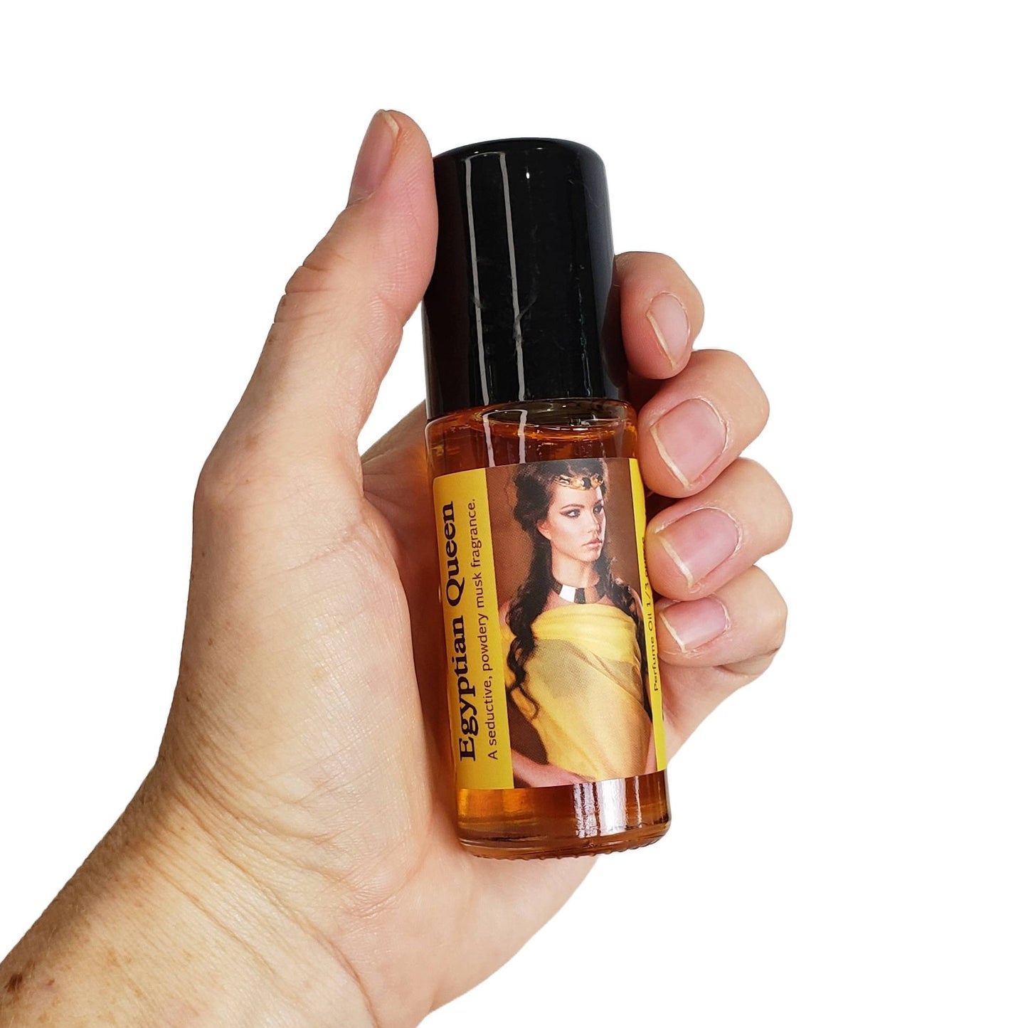 large one ounce bottle of egyptian queen perfume oil, a seductive musk fragrance oil, shown held in a hand for scale, with a white background