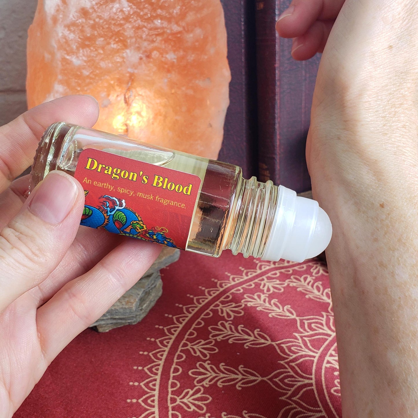 showing how to apply dragon's blood perfume oil to wrist, using the larger one ounce bottle with rollerball