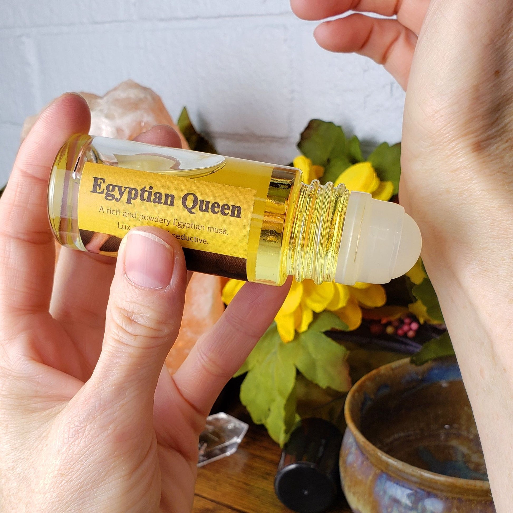 applying egyptian queen perfume oil to the wrist with the larger 1 ounce roll-on bottle