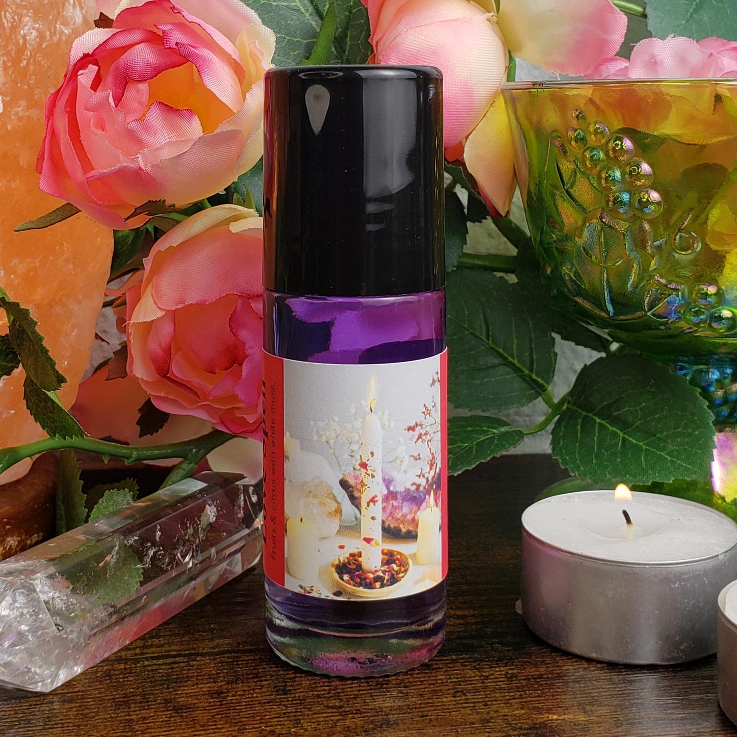 The front of the Love Spell perfume oil bottle, showing the label art and black cap that covers the rollerball