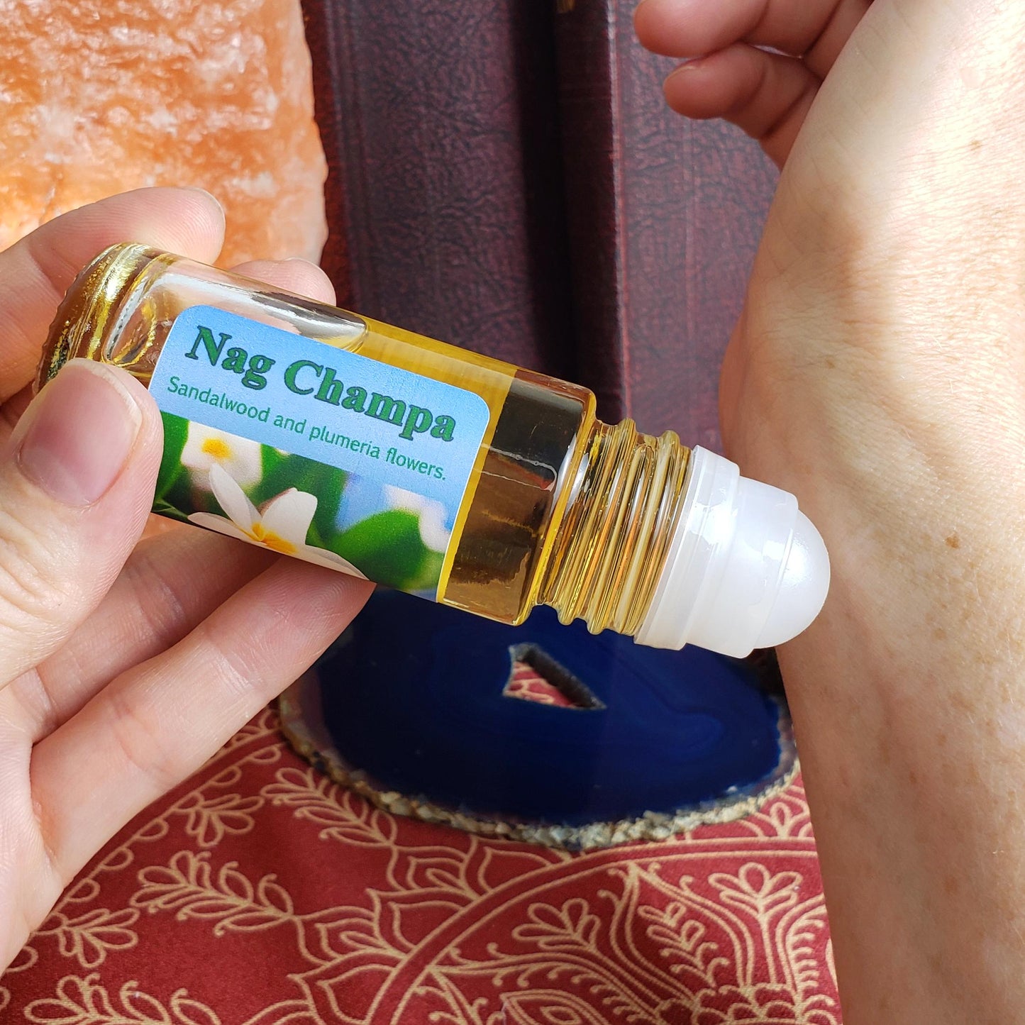 Applying Nag Champa perfume oil to wrist using the rollerball, and the larger one ounce bottle.