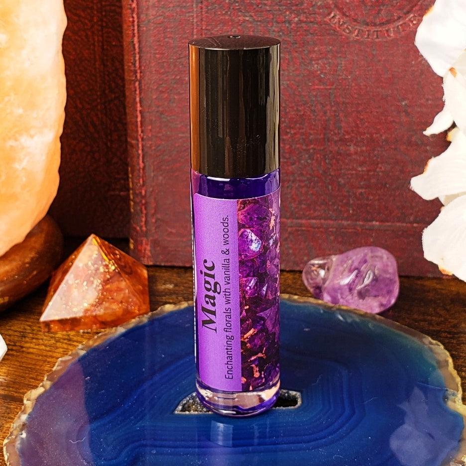 Purple rollerball bottle labeled 'Magic' on a blue crystal with crystals and books in the background